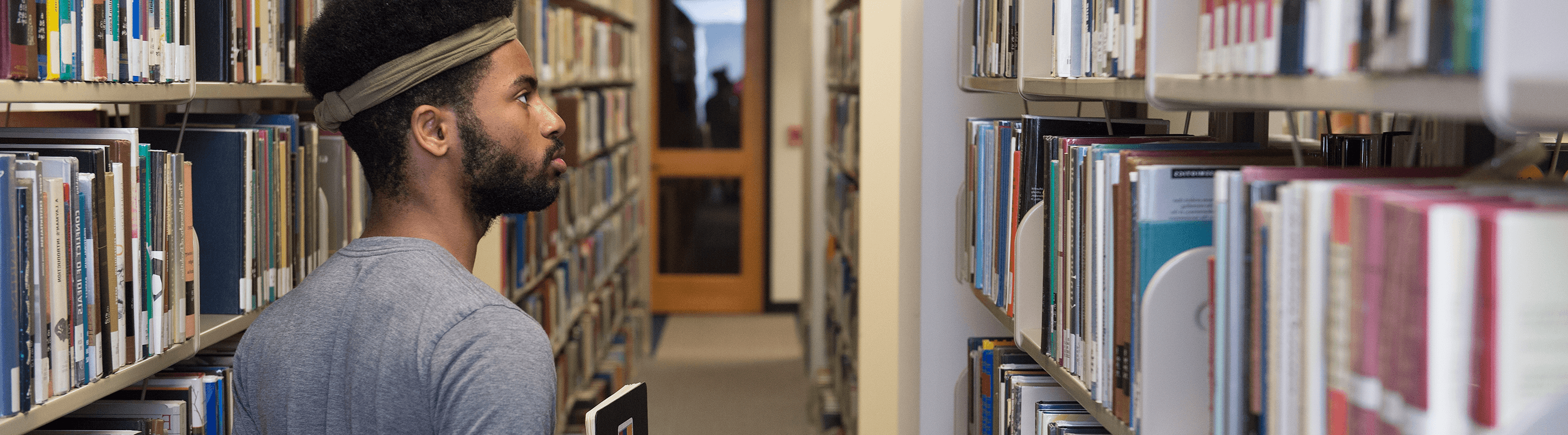 Student looking through books at the library